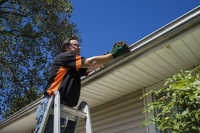 a skilled worker fixing broken gutter on a roof in Brooklyn Heights